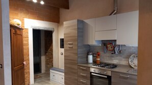 A modern kitchen with a stone fireplace, wooden cabinets, and a built-in oven. - Clery house, a stone's throw from Florence, Tuscan style (Montelupo Fiorentino)