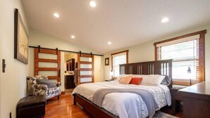 Ein Schlafzimmer mit einem großen Bett, einem Sessel, einem Schreibtisch und einer Schiebetür.