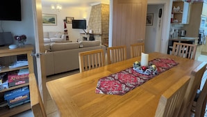 A dining area with a wooden table, chairs, and a red floral runner. A fireplace is visible in the background. - Birchcroft Hideaway (Ferndown)
