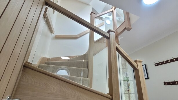 A wooden staircase with glass railings leading to a second floor. - Birchcroft Hideaway (Ferndown)