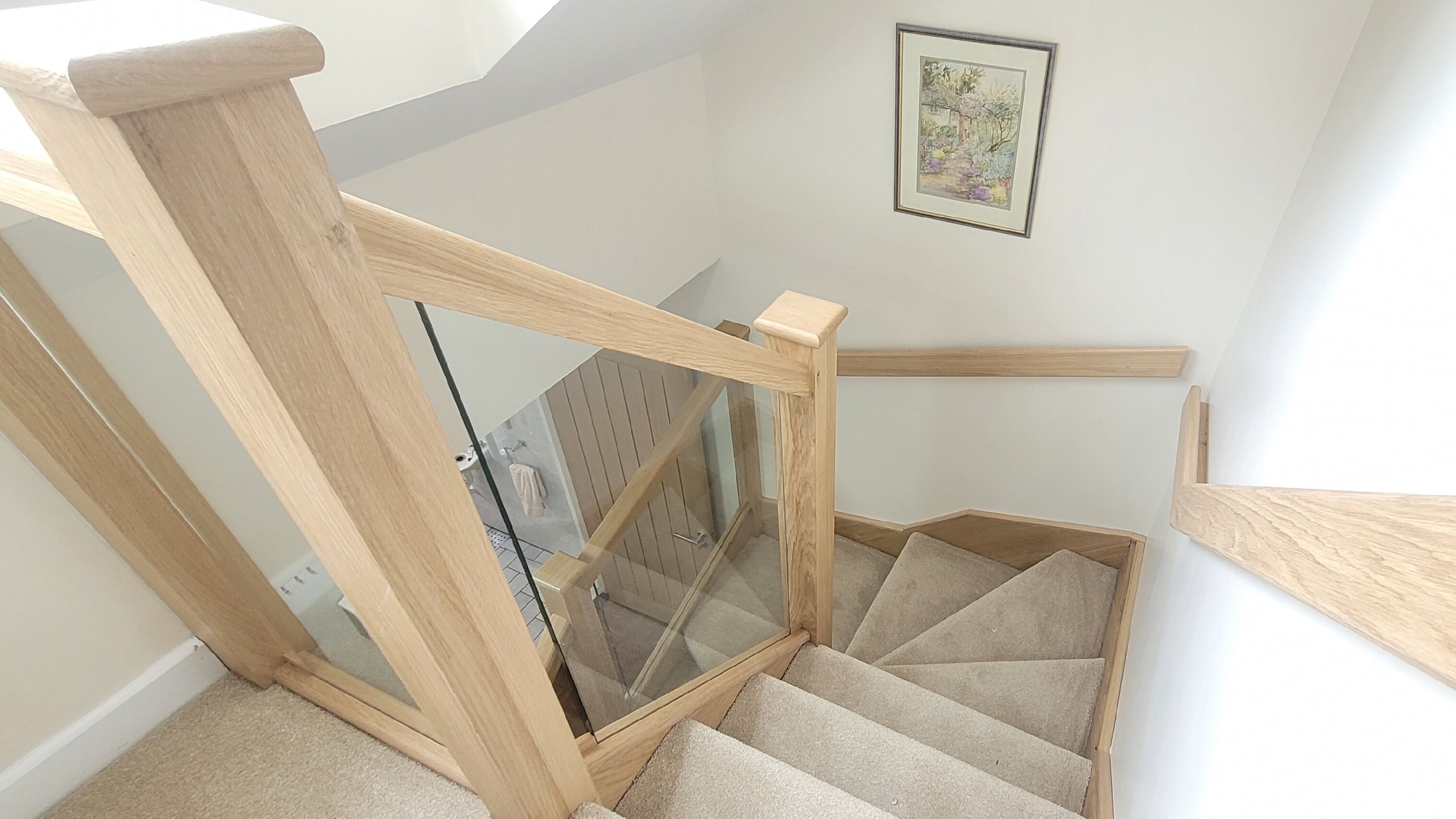 A wooden staircase with glass railings leading to an upper floor.