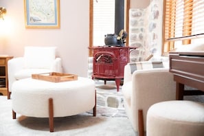 A cozy living room with a round white ottoman, a red vintage stove, and a stone fireplace. - Whitefish 3 Bdrm, near ski&town w/views & hot tub (whitefish)