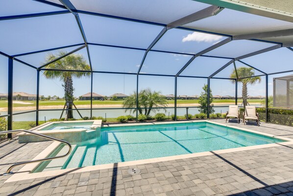 A covered outdoor swimming pool with a view of a lake and palm trees. - Punta Gorda Home w/ Lanai & Golf Course View! (Punta Gorda)