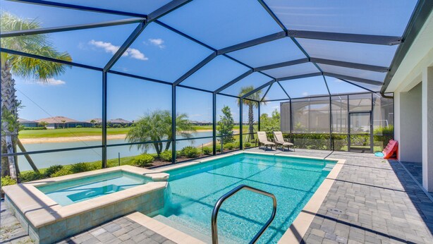 En utomhuspool med tak, med utsikt över en sjö, solstolar och en liten bubbelpool.