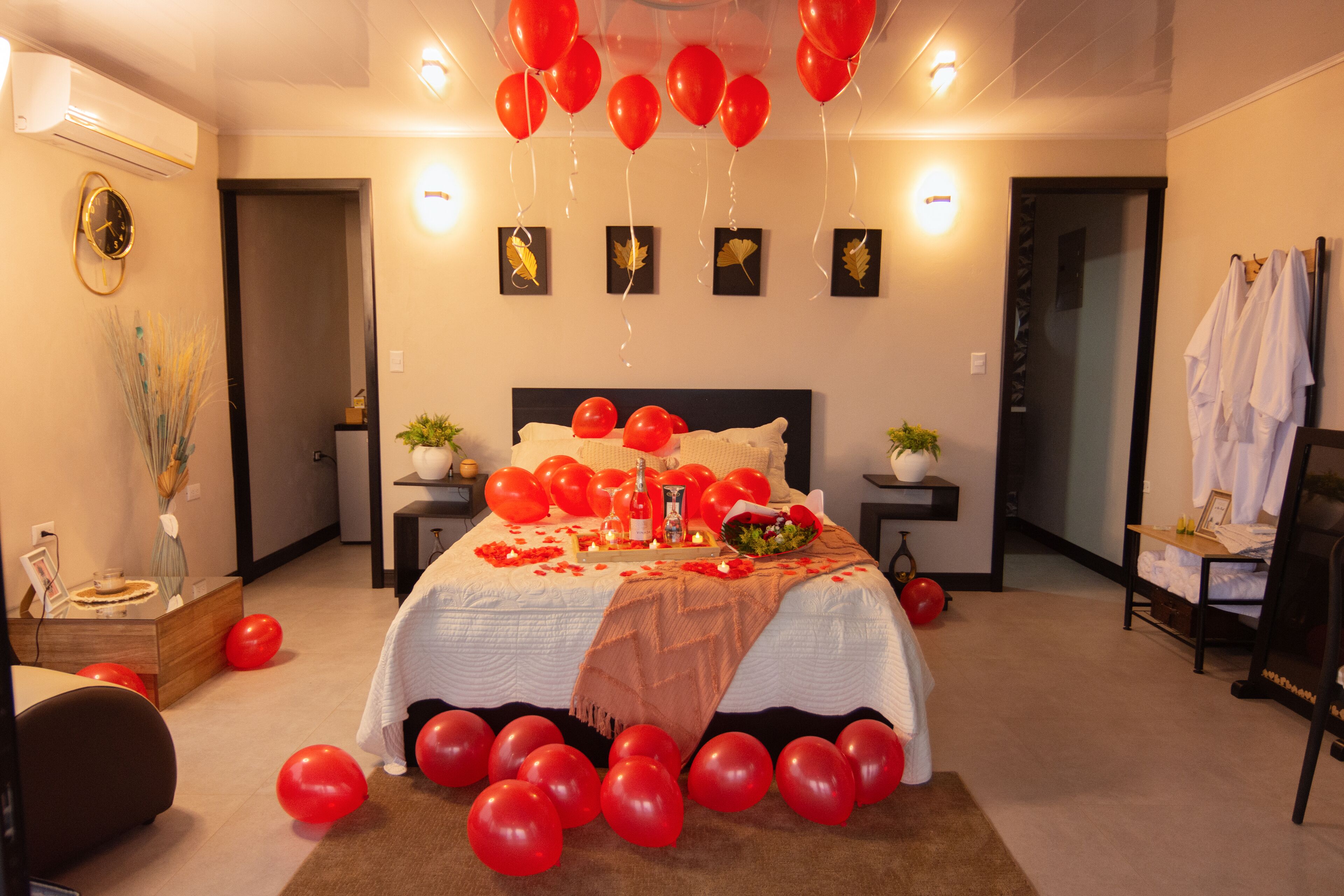 Ein Schlafzimmer mit einem Bett, roten Ballons und einem Blumenstrauß.