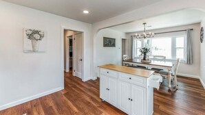 A spacious kitchen with a wooden countertop, white cabinetry, and a dining area with a chandelier.