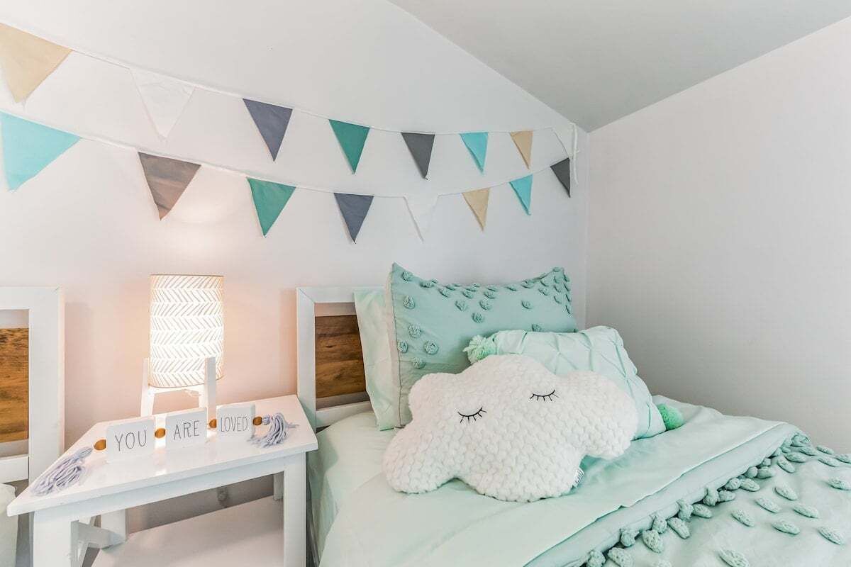 Un dormitorio con cama, mesita de noche, lámpara y un adorno en la pared.