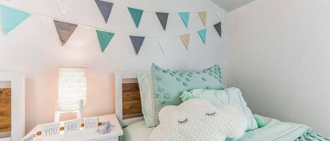 Un dormitorio con cama, mesita de noche, lámpara y un adorno en la pared.