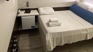 A small, clean room with a bed, a desk, and a TV.