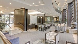 Un hallo amplio con una escalera curva, una zona de bar con asientos y un gran ventanal que proporciona luz natural.