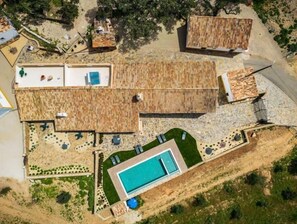 Vista aérea de uma propriedade com piscina, várias construções de madeira e um jardim bem cuidado.