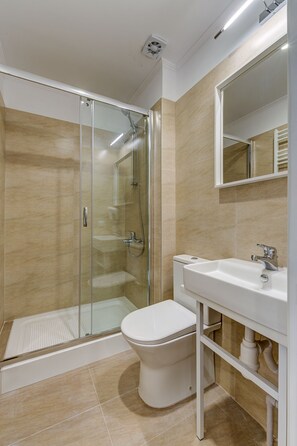 Standaard driepersoonskamer | Badkamer | Een douche, een haardroger, pantoffels, handdoeken
