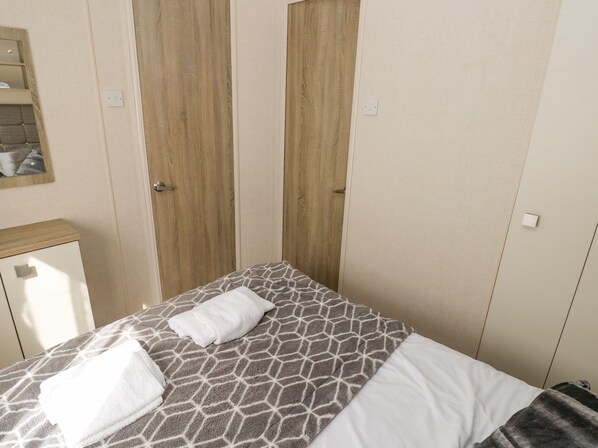 A bedroom with a bed, a nightstand, and a wardrobe. - 116 Woodpecker Lodge (New Quay)