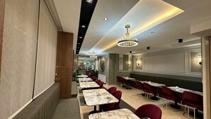 A modern restaurant interior with marble-topped tables, red upholstered chairs, and a chandelier. - Paradise Suit Otel  (Beysehir)