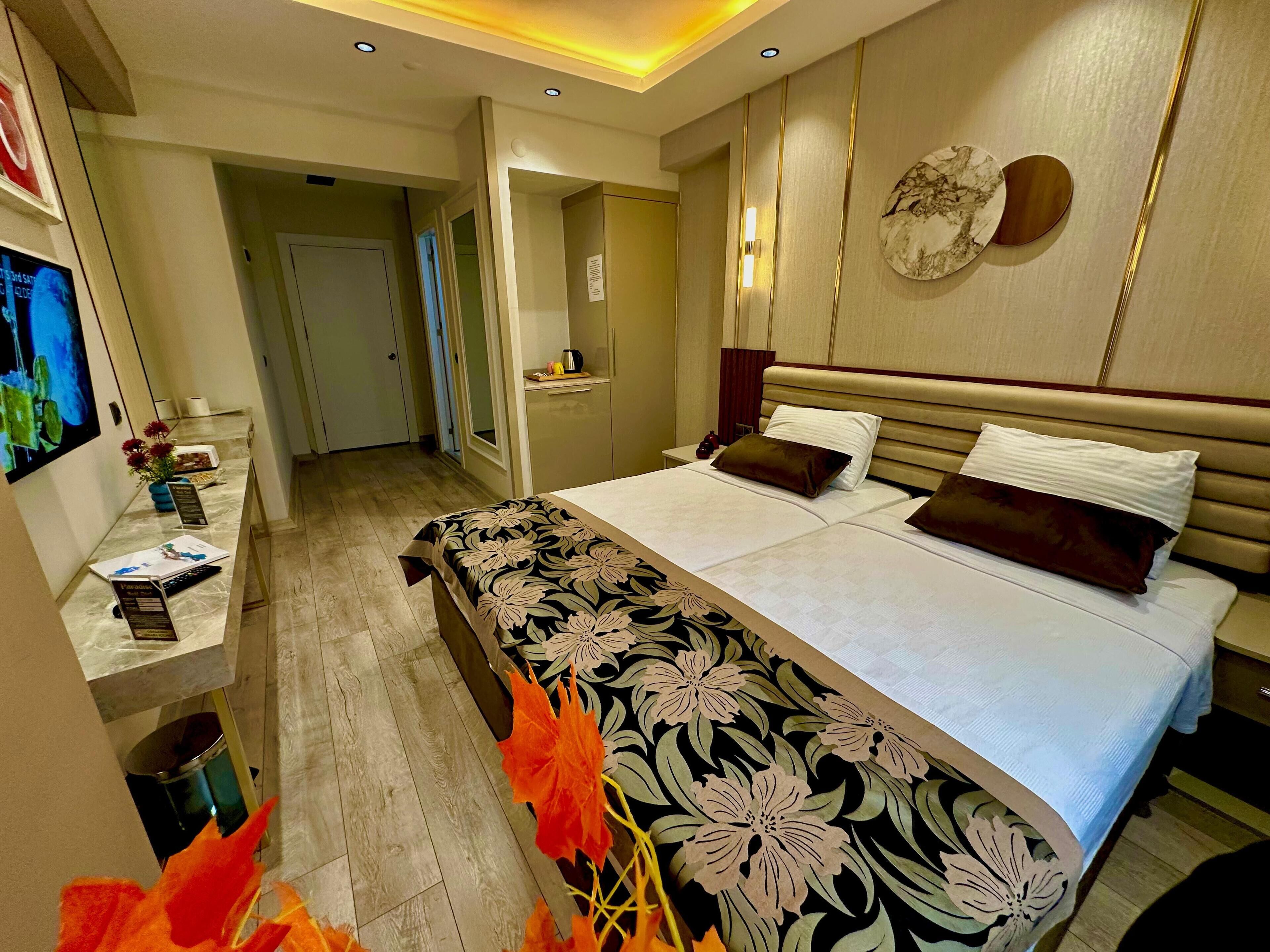 Habitación de hotel con una cama grande, una mesita de noche, un televisor y un baño visible a través de una puerta abierta.