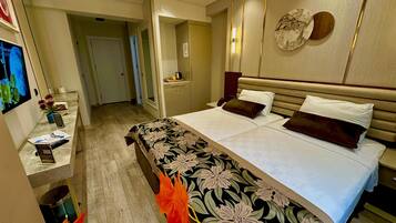 Habitación de hotel con una cama grande, una mesita de noche, un televisor y un baño visible a través de una puerta abierta.