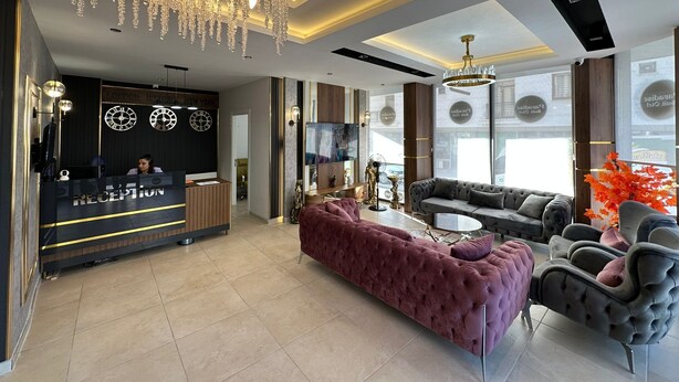 A modern reception area with a reception desk, seating area with sofas, and a chandelier. - Paradise Suit Otel  (Beysehir)