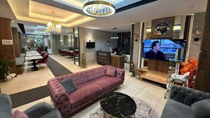 A modern hotel lobby with a reception desk, seating area, and a dining area. - Paradise Suit Otel  (Beysehir)