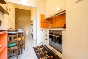A compact kitchen with white cabinets, an oven, and a tiled backsplash. - Cozy ground floor apartment with garden 1.5Km from the beaches   (Viareggio)