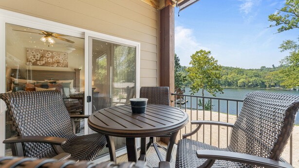 A deck with wicker furniture, a table, and a view of a lake. - Lakefront Luxury:
NoStairs/King beds
Wheelchair Accessible
Families/Couples/Pets (Branson)