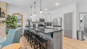 A modern kitchen with white cabinets, stainless steel appliances, a central island with bar stools, and pendant lighting. - Lakefront Luxury:
NoStairs/King beds
Wheelchair Accessible
Families/Couples/Pets (Branson)