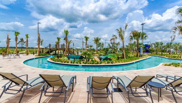 A pool area with lounge chairs, palm trees, and a covered seating area.