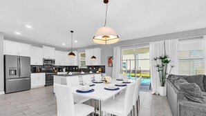A modern kitchen with white cabinets, stainless steel appliances, and pendant lighting.