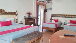 Habitación de hotel con dos camas, un banco de madera, una mesa redonda con un control remoto y una chimenea.