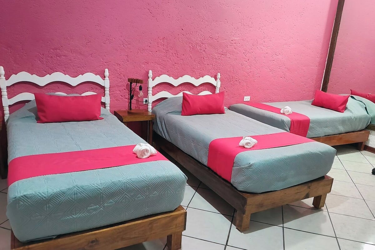 A room with three beds, each with a wooden frame and a headboard.