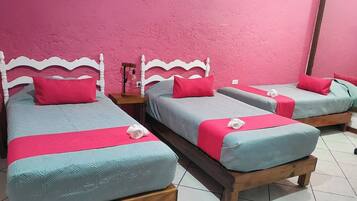 A room with three beds, each with a wooden frame and a headboard.