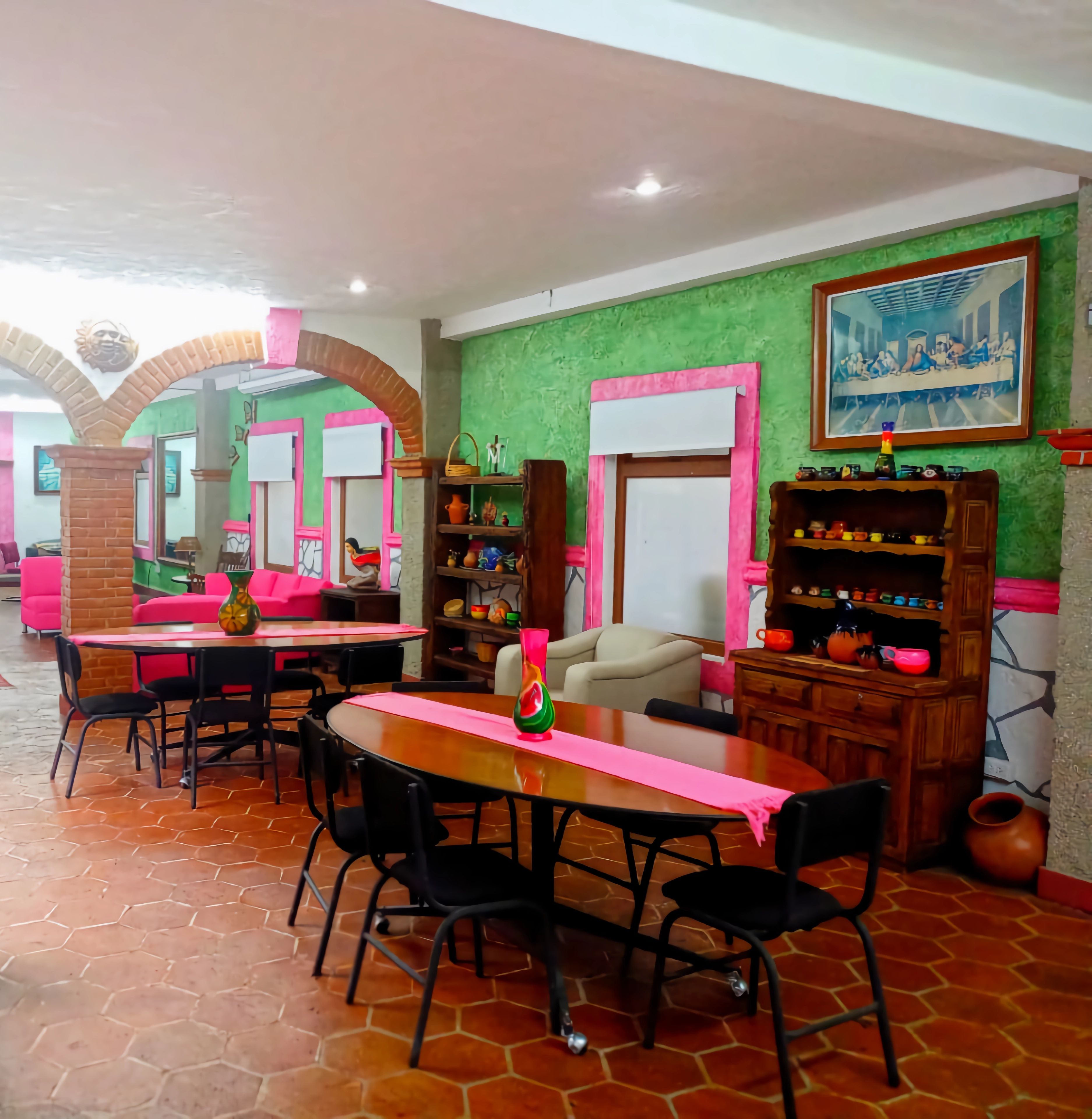 Un comedor con suelo de patrón hexagonal, una mesa central con sillas y una zona de estar con sofá y sillones.