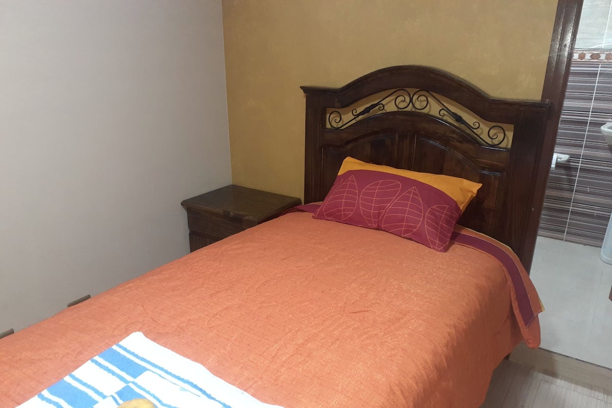 Ein Bett mit Holz Kopfteil, einem gestreiften Handtuch und einer Frucht darauf.