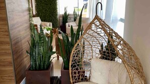 A modern interior with a hanging chair, potted plants, and a green wall. - AP 1422 com Piscina, Academia e Coworking (Juiz de Fora)