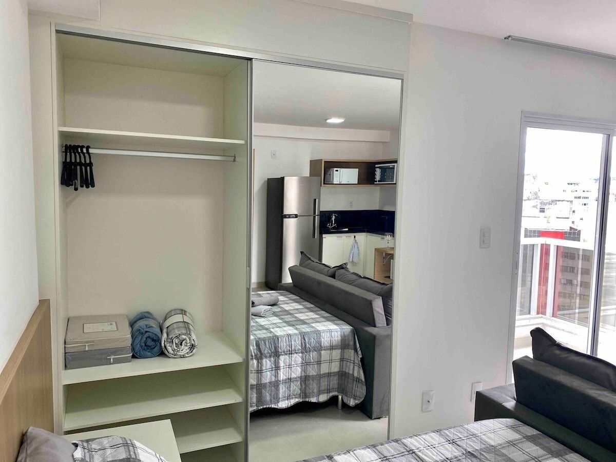 A modern bedroom with a bed, a wardrobe, and a kitchenette.