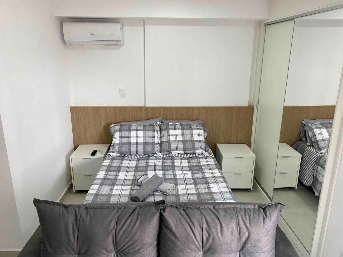 Une chambre à coucher comprenant un lit, deux tables de chevet, une armoire et un miroir.
