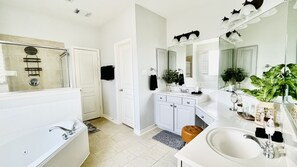 A modern bathroom with a large bathtub, a vanity with a mirror, and a sink. - Waterfront King - Sleeps 10 , Media Room , Deck on Water , Fishing & Kayaking (Missouri City)