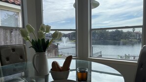 Une table à manger avec une assiette d’œufs, un bol de pain, un verre de thé et un vase de tulipes.