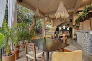 A dining area with a large table, chairs, hanging lights, potted plants, and a staircase leading to an upper level. - Mountain Paradise Retreat: Casanevo-Tepoztlan (Tepoztlán)