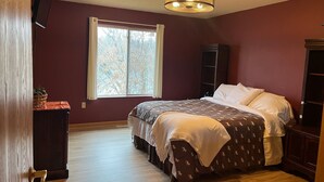 Un dormitorio con cama, ventana, ventilador de techo y suelo de madera.