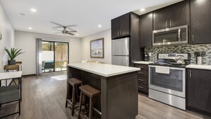 A modern kitchen with dark cabinets, stainless steel appliances, and a large island. - 30+ Days - North UT Apt 12 - 1 mi Moody Center (Austin)