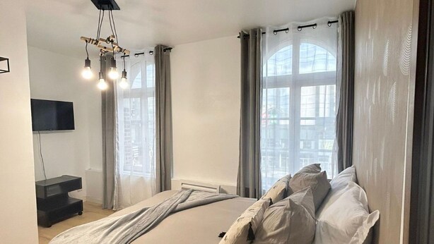 Une chambre moderne avec un grand lit, un téléviseur à écran plat et un luminaire au plafond.