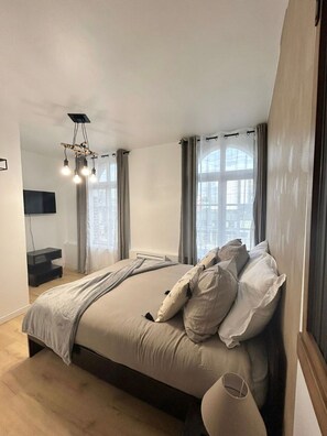 Quarto moderno com uma cama grande, televisão de tela plana e luminária no teto.