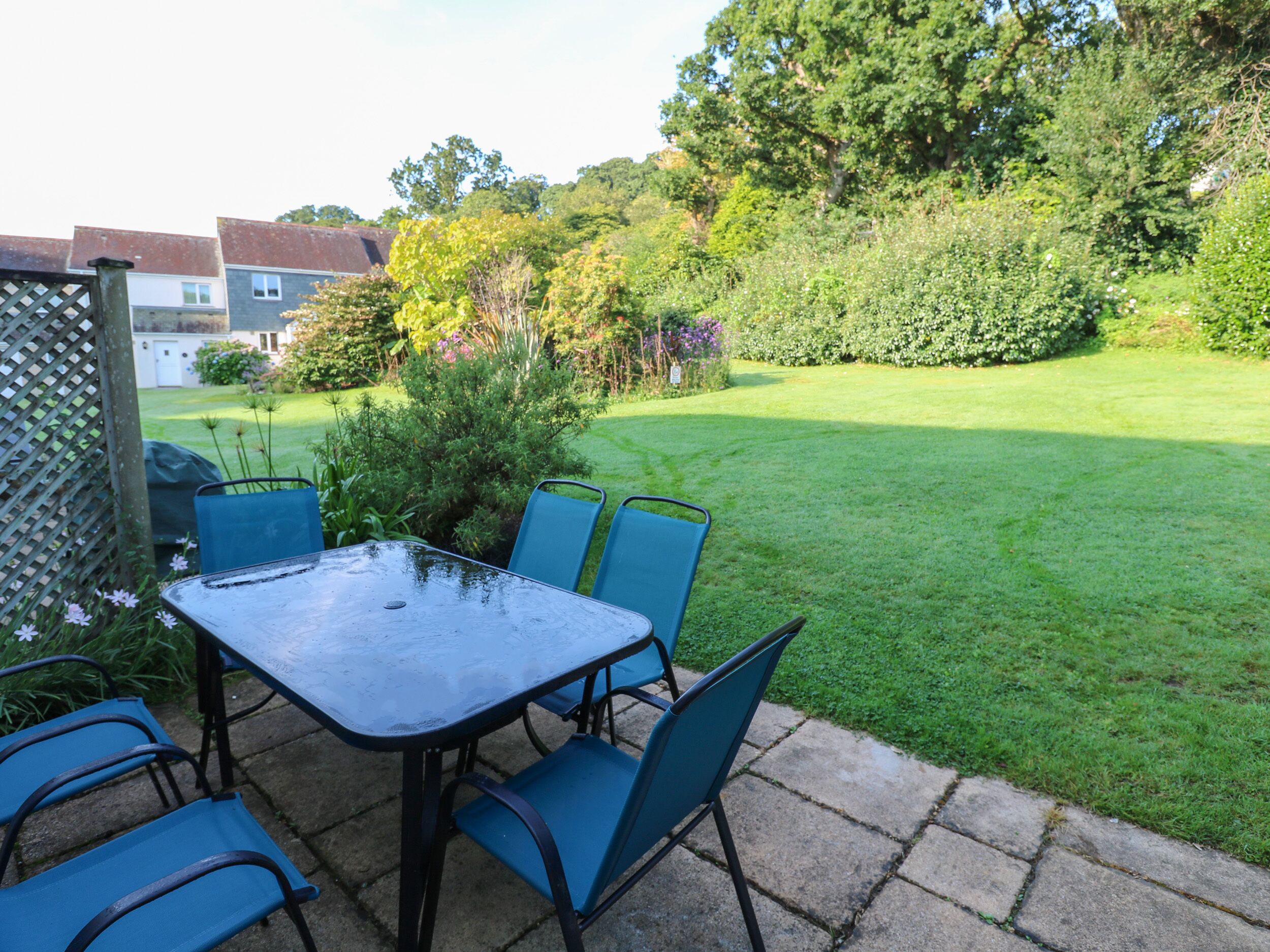 A patio with a table and chairs, surrounded by a well-maintained lawn and garden.