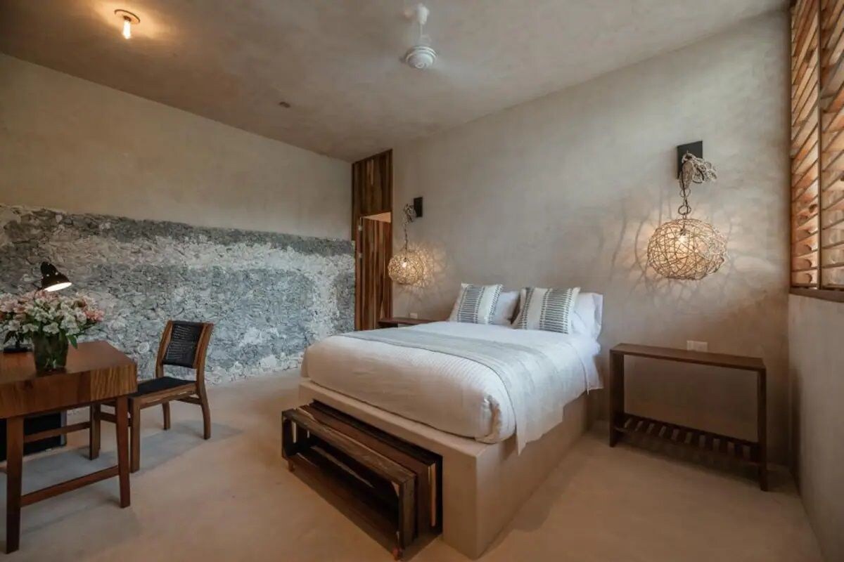 Ein Schlafzimmer mit einem großen Bett, einem Holznachttisch, einem Tisch mit Stühlen und einer Wandleuchte.