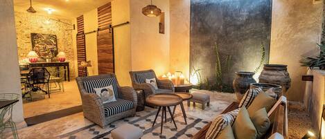 Un rincón tranquilo con muebles de mimbre, una alfombra estampada y velas.