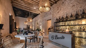 A cozy bar area with wicker chairs, a marble table, and a stone wall backdrop. - Casa Kacaya (Espita)