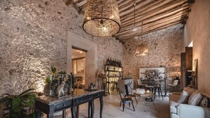 A rustic interior with exposed stone walls, a wooden ceiling, and a bar area with a bookshelf. - Casa Kacaya (Espita)