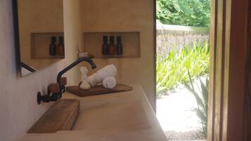 Bathroom features a large mirror, single sink, and wooden shelf with storage.