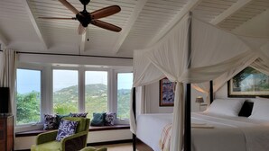 A bedroom with a bed, a ceiling fan, a window with a view, and a green armchair. - 3 Minutes Drive to Famous Magens Bay Beach (St Thomas)