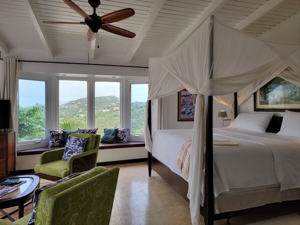A bedroom with a bed, a ceiling fan, a window with a view, and a green armchair. - 3 Minutes Drive to Famous Magens Bay Beach (St Thomas)